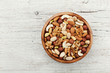 © juliasudnitskaya - Wooden bowl with mixed nuts on white table from above. Healthy food and snack. Walnut, pistachios, almonds, hazelnuts and cashews.