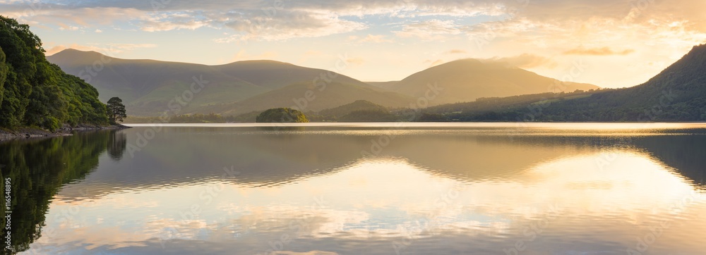 Golden sunlight shining through mountains on peaceful calm morning at Derwentwater, Lake District, UK. - obrazy, fototapety, plakaty 