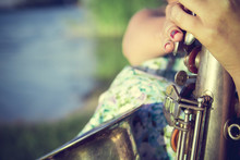 Photo Central Part Of Saxophone In Hands Of Young Woman Sitting