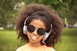© Africa Studio - Afro-American little girl with sunglasses and headphones chewing bubblegum in park
