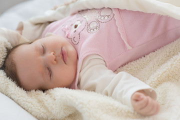 Newborn baby sleeps on the bed in woolen clothes