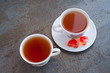 Чай в двух чашках и красные карамельные сердца на блюдце на фоне дерева серого цвета. Вид сверху.