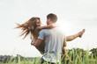 © Jacob Lund - Man carrying girlfriend in  grass field