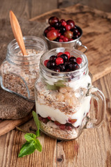 Muesli, fresh berries and yogurt in glass mason jar on wooden ta