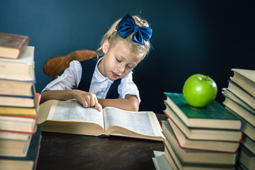 Smart school girl reading a book at library