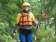 © atomfotolia - Young woman walking through the woods with two paddles and a helmet