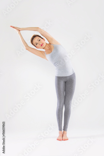 Poster Beautiful young woman doing yoga on a gray studio background