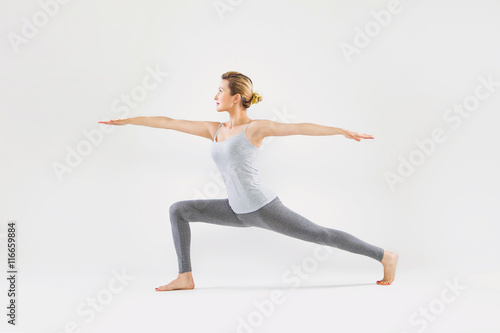 Poster Schöne junge Frau auf einem grauen Hintergrund Studio Yoga tut