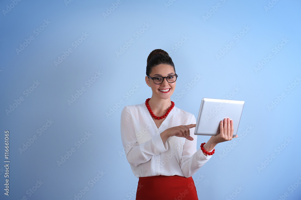 Pretty young woman holding tablet on light background