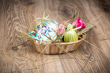 Easter eggs in the wicker on wooden background