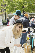 Young Woman Bending While Man Reading Book At Flea Market