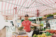 © Astrakan Images - Happy male vendor selling fruits at market stall