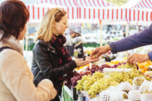 Mature Woman Buying Grapes At Market Stall
