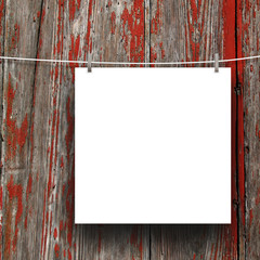 Wall Mural - Close-up of one blank square frame hanged by pegs against red scratched wooden boards background