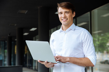 Happy businessman holding and using laptop