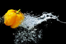 Fresh Yellow Pepper Falling In Water On Dark Background