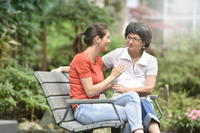 Senior woman with carer sitting on bench at the park