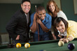 © digitalskillet1 - Group of young friends playing billiard.