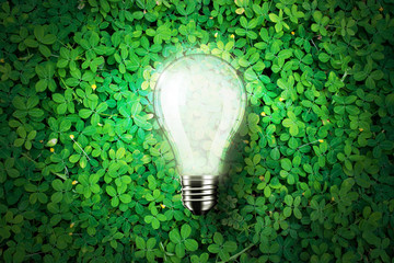 Wall Mural - Glowing light bulb is on green grass background , concept idea