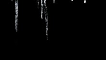 Time Lapse of icicles forming over a black background.