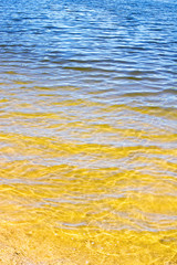 transparent water ripple, sand bottom and reflection of blue sky