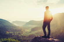 Traveler Young Man Standing In Summer Mountains At Sunset And Enjoying View Of Nature