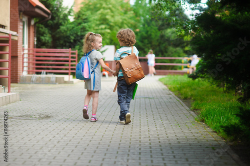 Fototapeta Young students, boy and girl, going to school