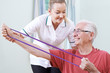 © highwaystarz - Physiotherapist Helping Senior Male To Use Resistance Band