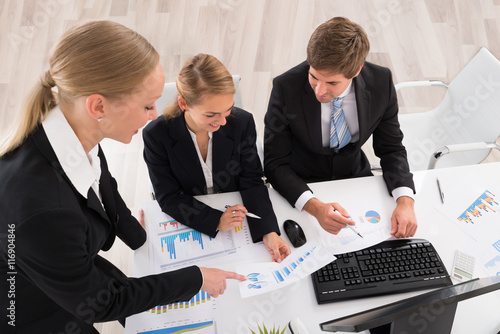 Happy Young Businesspeople Working On Graphs плакат