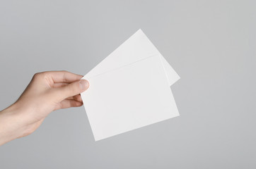 A6 Flyer / Postcard / Invitation Mock-Up - Male hands holding blank flyers on a gray background.