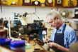 © Mint Images - A clock maker busy in his workshop.