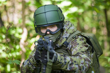 A Man In A Military Uniform In The Woods With A Gun