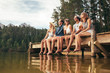 © Jacob Lund - Group of friends sitting on jetty at lake