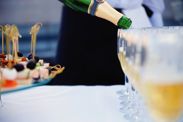 The waiter pours champagne into a glass