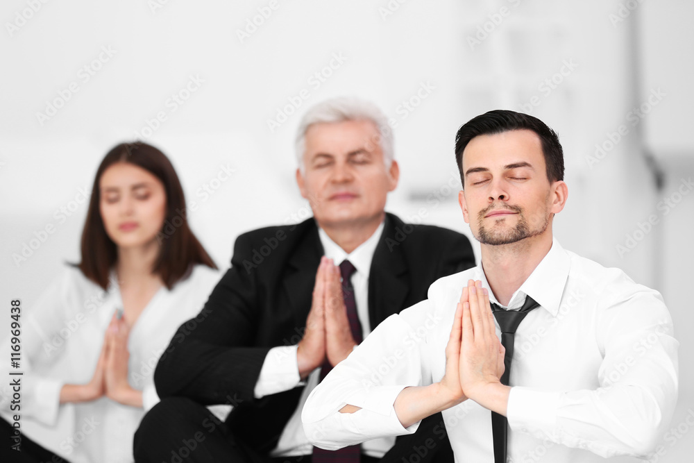 Business people relaxing in meditation pose in office