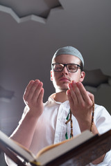 Wall Mural - Young muslim man is praying in the mosque