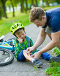 © Ermolaev Alexandr - father putting band-aid on young boy's injury who fell off his bike