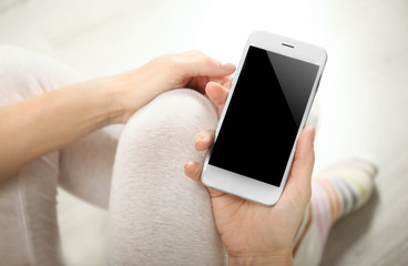 Wall Mural - Woman holding smartphone on blurred carpet background