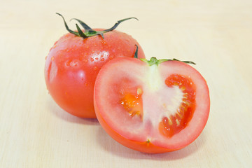 Tomato fruit with half cross section isolated on wooden backgrou