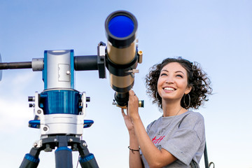 Wall Mural - girl looking through a telescope outdoors