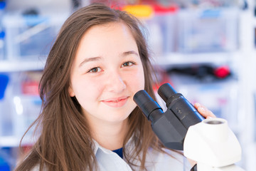 Poster - Biology lesson. Female Teenage Student In Science Class With Experiment on Microscope