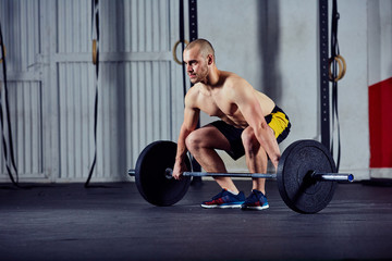 Wall Mural - Young athlete doing weightlifting workout with barbell at the gy