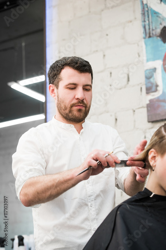Male hairdresser making haircut for a client in professional hairdressing salon Slika na platnu