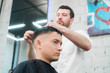 © romankosolapov - Professional styling. Close up side view of young man getting haircut by hairdresser with electric razor at barbershop