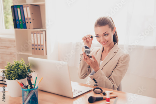 Fényképezés Portrait of pretty businesswoman painting her eyelashes with mas