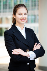 Wall Mural - Portrait of a young smiling businesswoman with folded arms