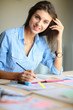 © lenets_tan - Young woman sitting at the desk with instruments, plan and laptop