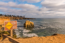 Danger Sign With Bird Rock In Background At Sunset Cliffs In San Diego, California.  