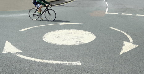 Small white roundabout with bicyclist passing by