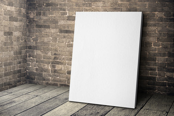 blank white canvas frame leaning at grunge brick wall and wood f